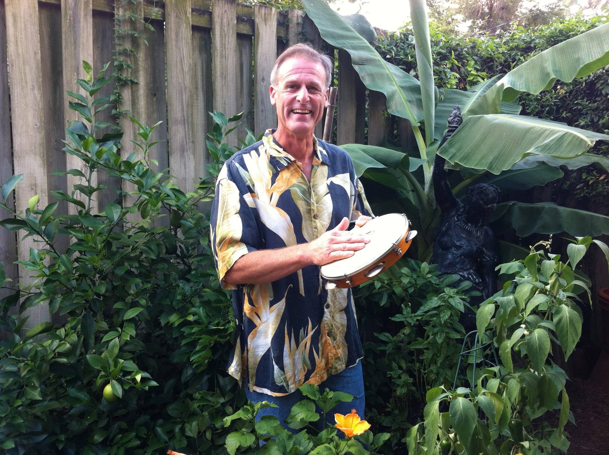 Andrew Hartzell outdoors, smiling and holding a pandeiro